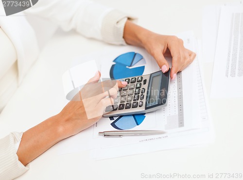 Image of businesswoman working with calculator in office