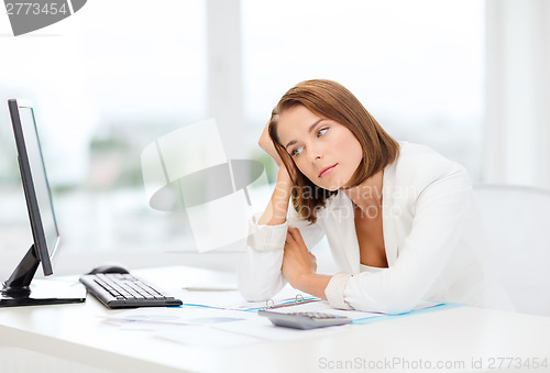 Image of tired businesswoman with computer and papers