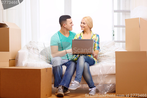 Image of couple relaxing on sofa with laptop in new home