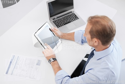 Image of businessman with tablet pc and papers in office