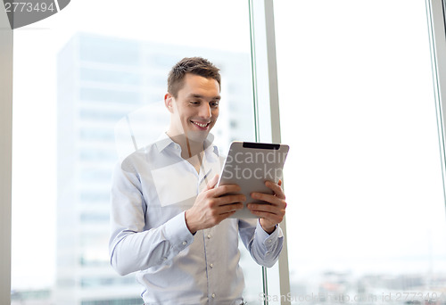 Image of smiling businessman with tablet pc in office