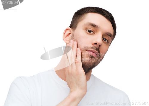 Image of beautiful calm man touching his face