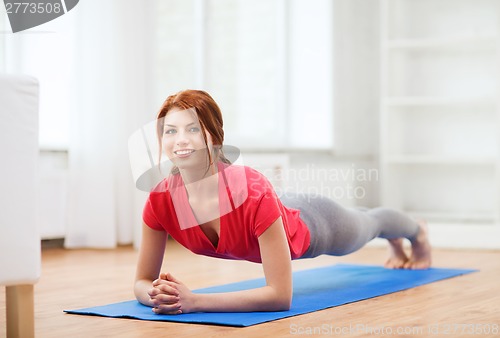 Image of smiling redhead teenage girl doing plank at home
