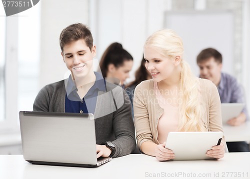 Image of two smiling students with laptop and tablet pc