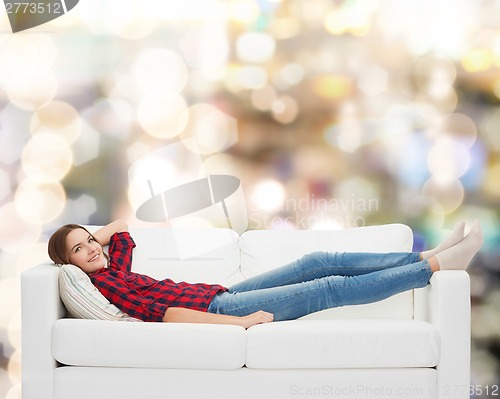 Image of smiling teenage girl lying on sofa