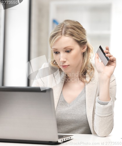 Image of serious woman with laptop computer and credit card