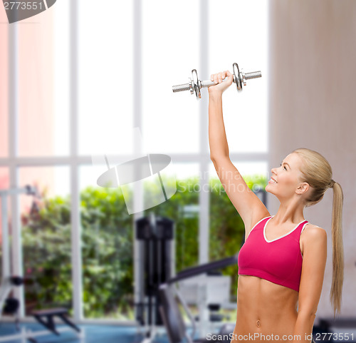 Image of smiling woman with heavy steel dumbbell