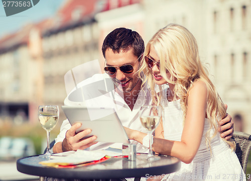 Image of couple looking at tablet pc in cafe