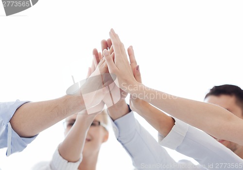 Image of happy business team giving high five in office