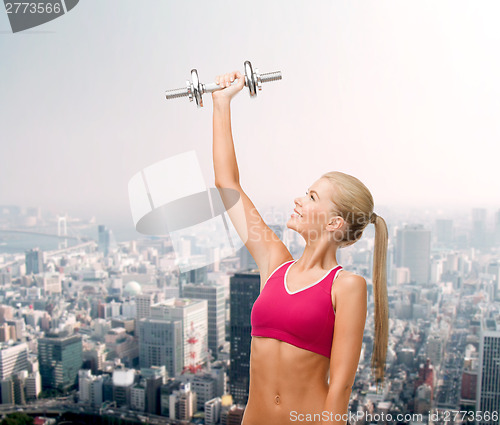 Image of smiling woman with heavy steel dumbbell