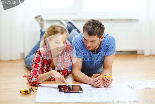 Image of smiling couple looking at tablet pc at home