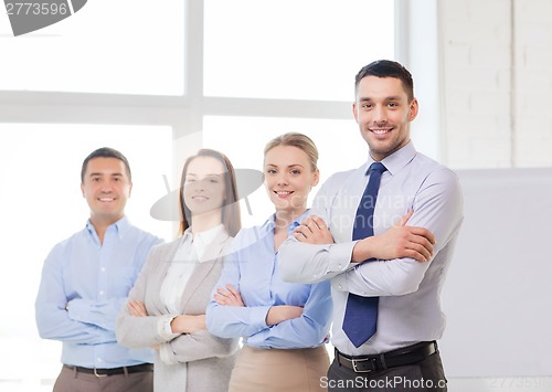 Image of smiling businessman in office with team on back