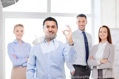 Image of smiling businessman showing ok-sign in office
