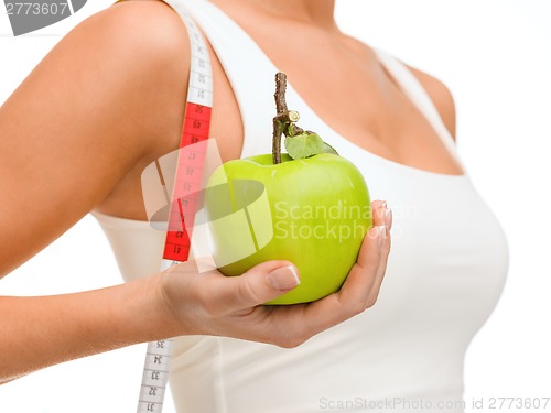 Image of female hand with apple and measuring tape