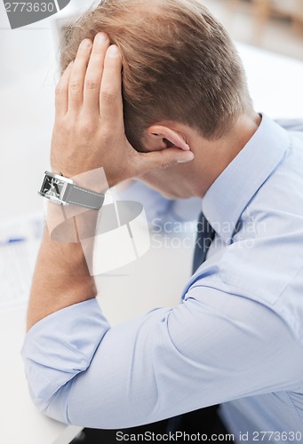 Image of stressed businessman with papers at work