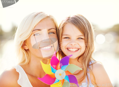 Image of happy mother and child girl with pinwheel toy