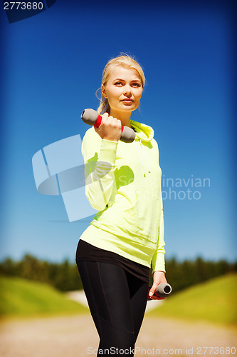 Image of sporty woman with light dumbbells outdoors