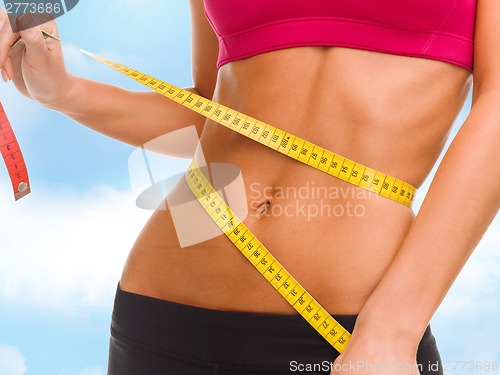 Image of close up of trained belly with measuring tape