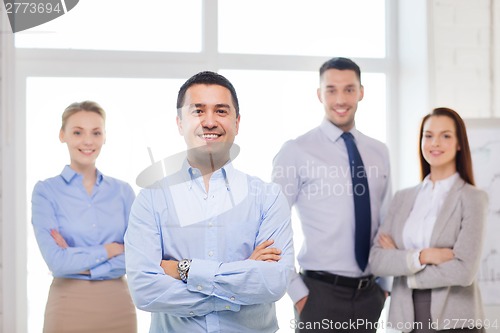 Image of smiling businessman in office with team on back