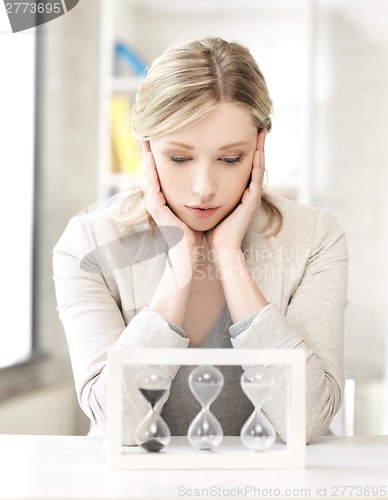 Image of pensive businesswoman with sand glass