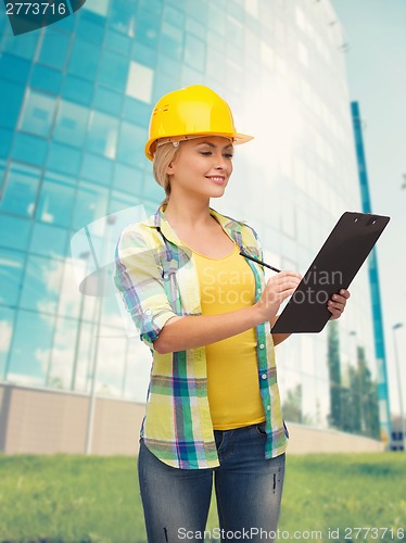 Image of smiling woman in helmet with clipboard