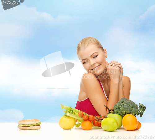 Image of doubting woman with fruits and hamburger