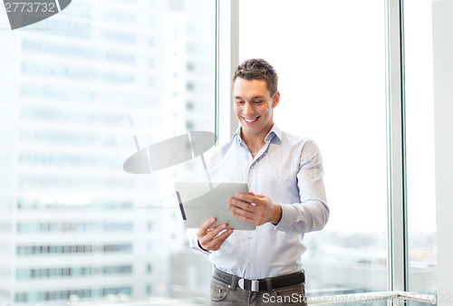 Image of smiling businessman with tablet pc in office