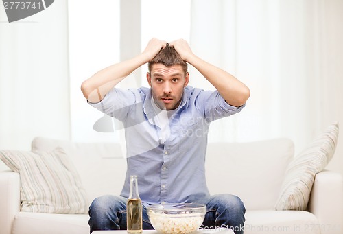 Image of sad man watching sports at home