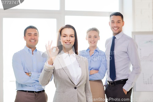 Image of smiling businesswoman showing ok-sign in office