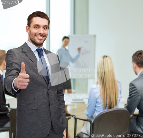 Image of handsome buisnessman showing thumbs up in office