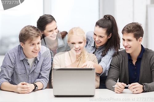 Image of smiling students looking at laptop at school