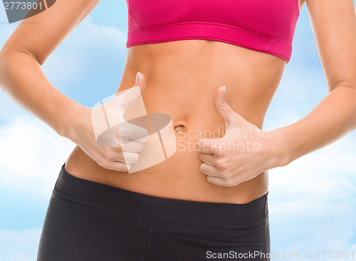 Image of close up of female abs and hands showing thumbs up