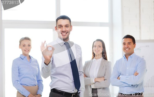 Image of smiling businessman showing ok-sign in office