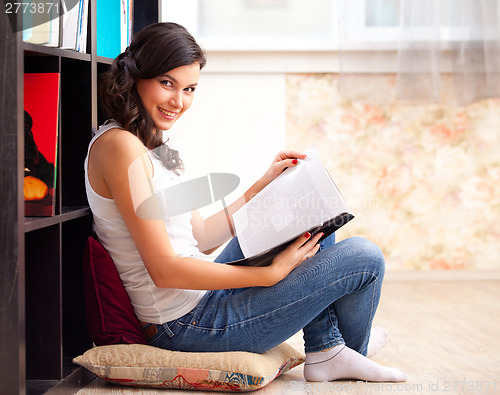 Image of student with a lbook in a library