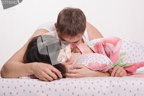 Image of Lovers embrace and kiss in bed