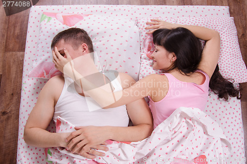 Image of She put hand on guy's face while sleeping in bed