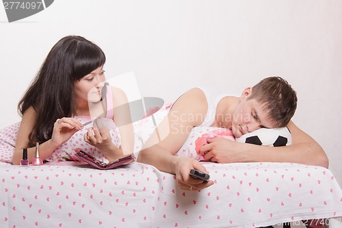 Image of wife looks at her husband sleeping football fan