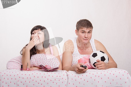 Image of Husband watches football, frankly bored wife