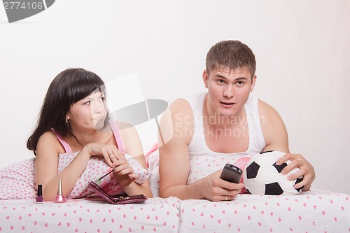 Image of Skeptical wife looking at her husband football fan
