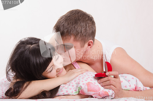 Image of Woman wakes guy kiss the ring in hands of