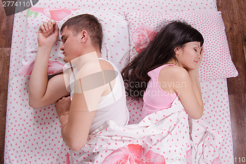 Image of girl and guy turned away from each other, sleeping bed