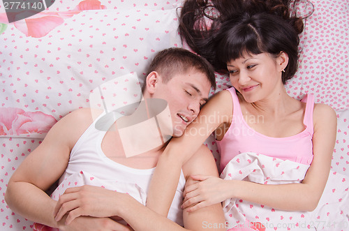 Image of girl looks at the sleeping guy lying in bed