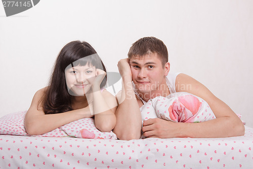Image of Happy young couple in bed smiling faces