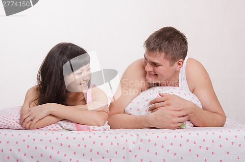 Image of Man and woman smiling at each other in bed