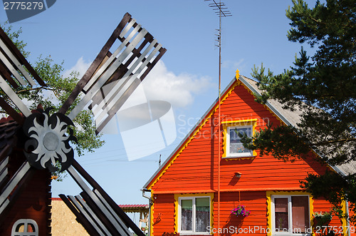 Image of red wooden house and brown decorative mill wind  