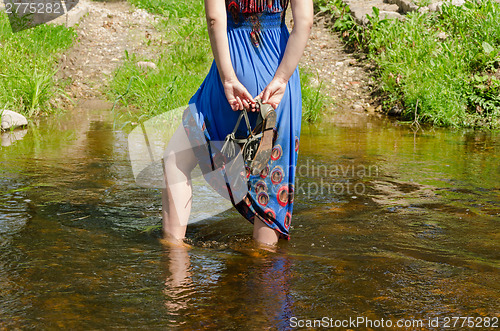 Image of girl legs with dress standing in flowing stream