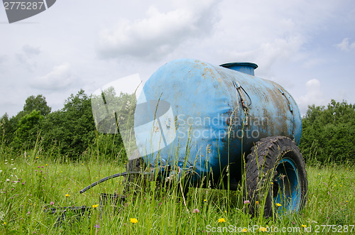 Image of Blue water cistern drink for farm animal in meadow 