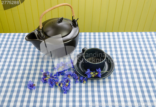 Image of clay tea set with fresh picked cornflower on table 