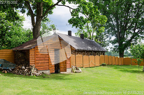 Image of handmade woodshed in village along wooden fence 