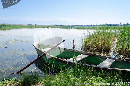 Image of old boat scratched paint with oars coast on spring 